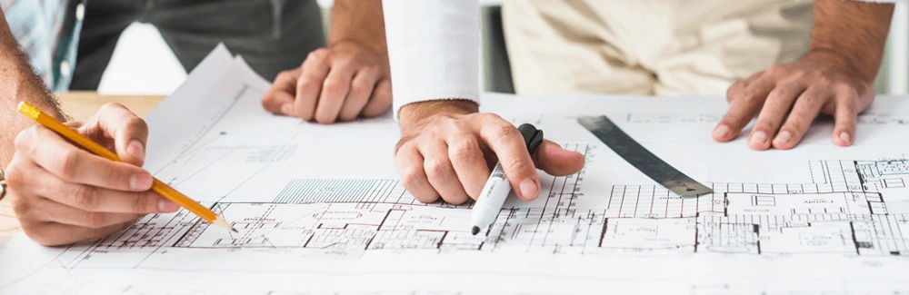 Project managers looking at paper plans on a desk